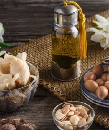 still-life-of-argan-oil-and-fruit-and-shea-butter-with-nuts-on-a-wooden-table-with-flowers