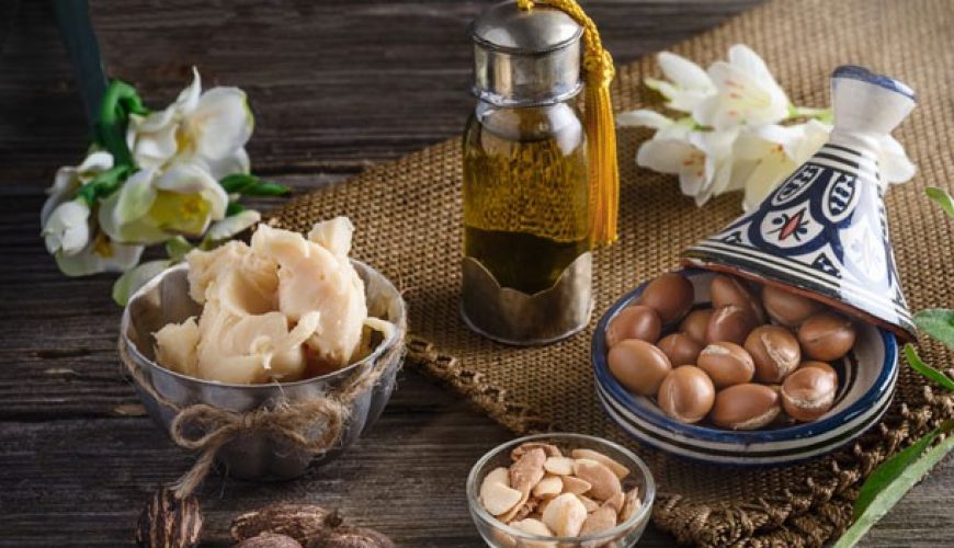 still-life-of-argan-oil-and-fruit-and-shea-butter-with-nuts-on-a-wooden-table-with-flowers