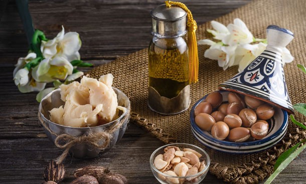 still-life-of-argan-oil-and-fruit-and-shea-butter-with-nuts-on-a-wooden-table-with-flowers